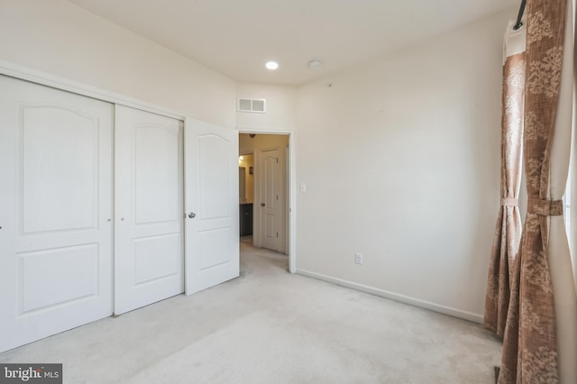 unfurnished bedroom with light carpet and a closet