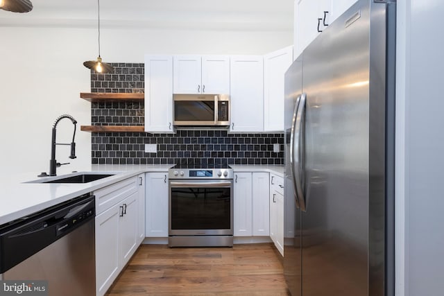 kitchen with dark hardwood / wood-style flooring, appliances with stainless steel finishes, decorative light fixtures, and white cabinets