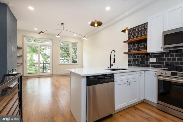 kitchen with sink, white cabinets, hanging light fixtures, and stainless steel appliances