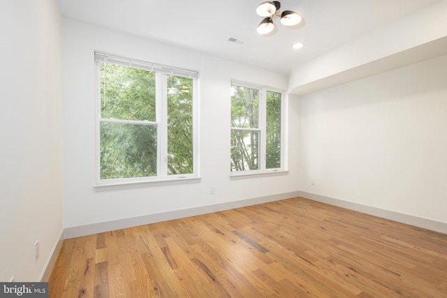 empty room with light hardwood / wood-style floors and an inviting chandelier