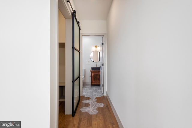 hall featuring a barn door and light hardwood / wood-style flooring