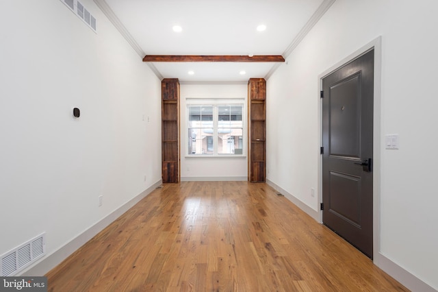 unfurnished room featuring crown molding, beam ceiling, and light wood-type flooring