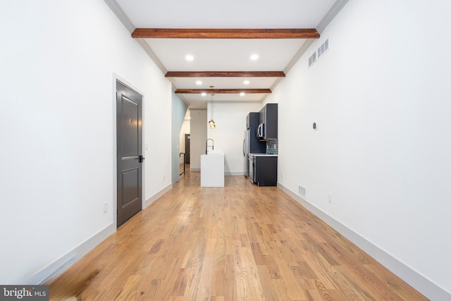 spare room featuring beamed ceiling and light wood-type flooring