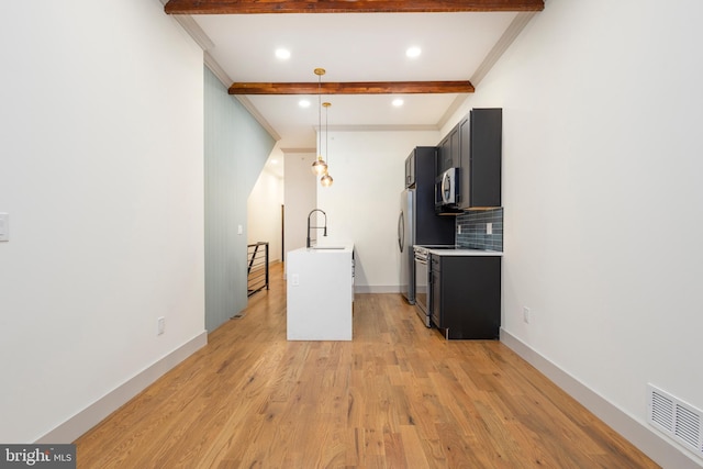 kitchen with decorative backsplash, beam ceiling, sink, pendant lighting, and appliances with stainless steel finishes