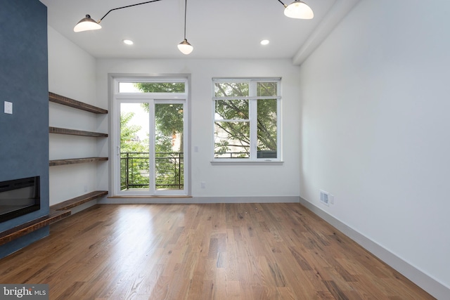 unfurnished living room with wood-type flooring and a healthy amount of sunlight