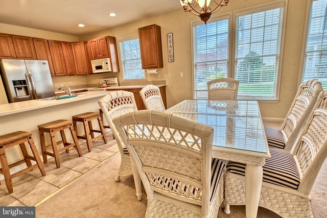 dining space with a wealth of natural light, sink, a chandelier, and light colored carpet