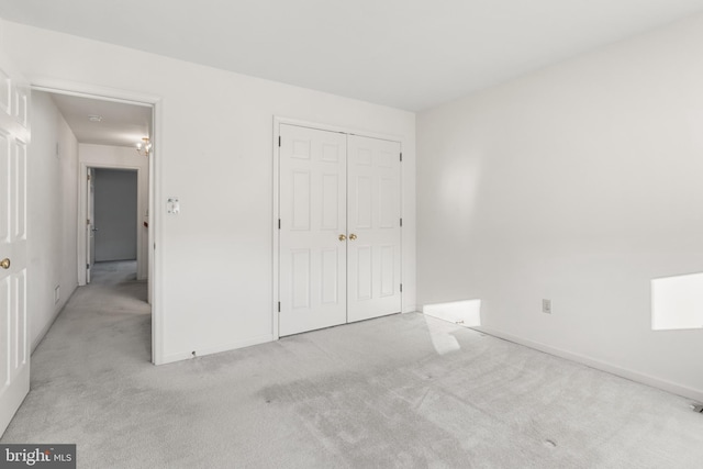 unfurnished bedroom featuring light carpet and a closet