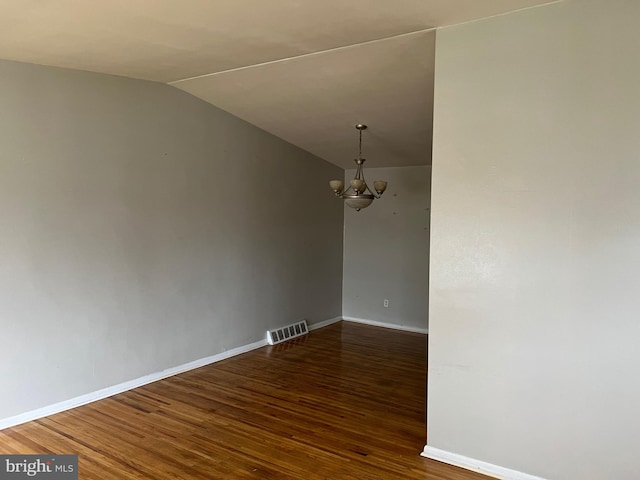 spare room with dark hardwood / wood-style flooring, lofted ceiling, and a chandelier