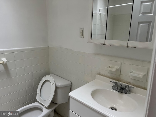 bathroom featuring vanity, tile walls, and toilet