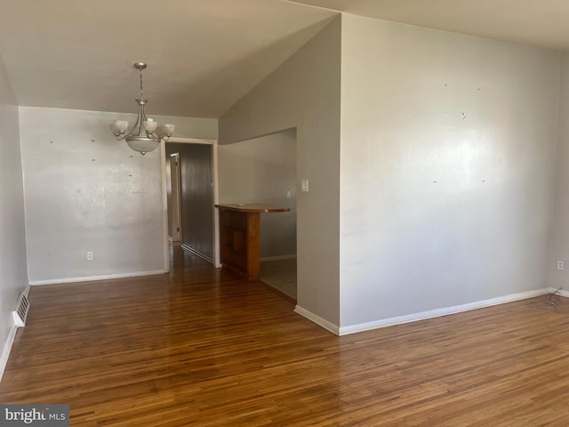 unfurnished dining area featuring a chandelier, dark hardwood / wood-style flooring, and vaulted ceiling