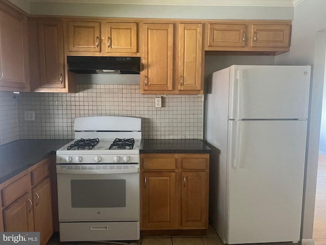 kitchen featuring light tile patterned floors, white appliances, and tasteful backsplash