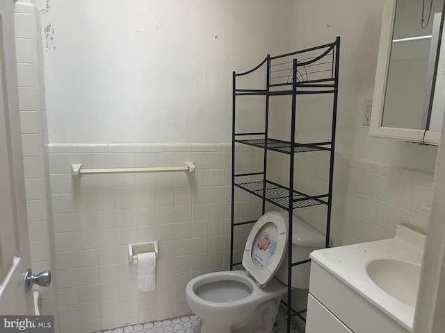 bathroom with tile patterned flooring, vanity, toilet, and tile walls