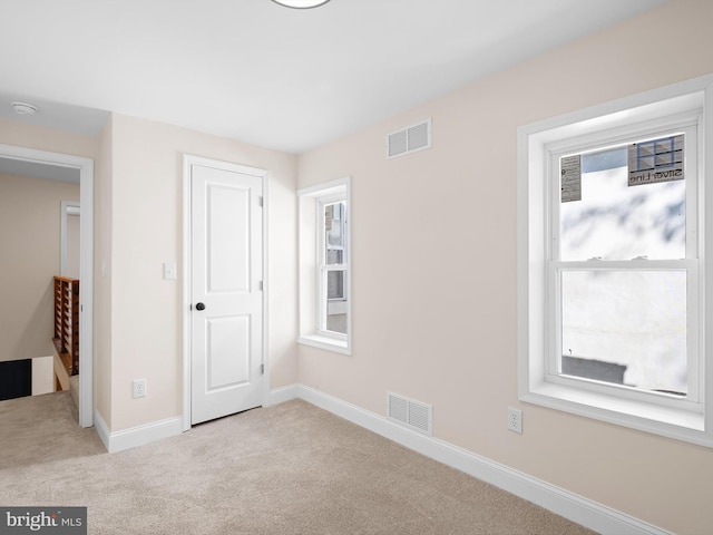 unfurnished bedroom with light carpet and multiple windows