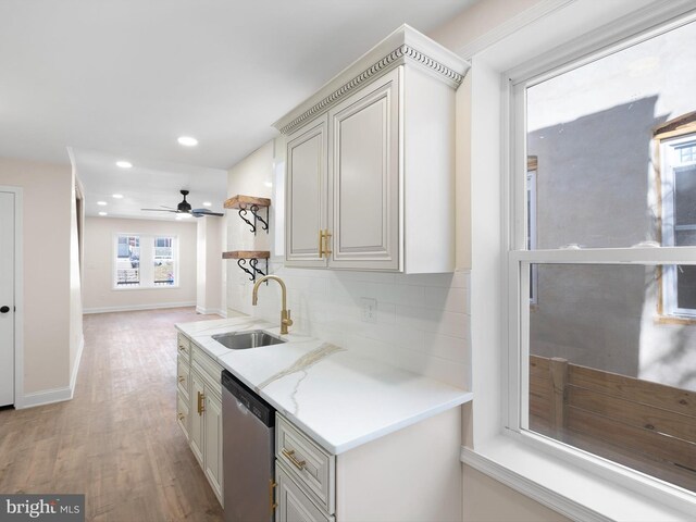 kitchen with tasteful backsplash, light stone counters, stainless steel dishwasher, light hardwood / wood-style flooring, and sink