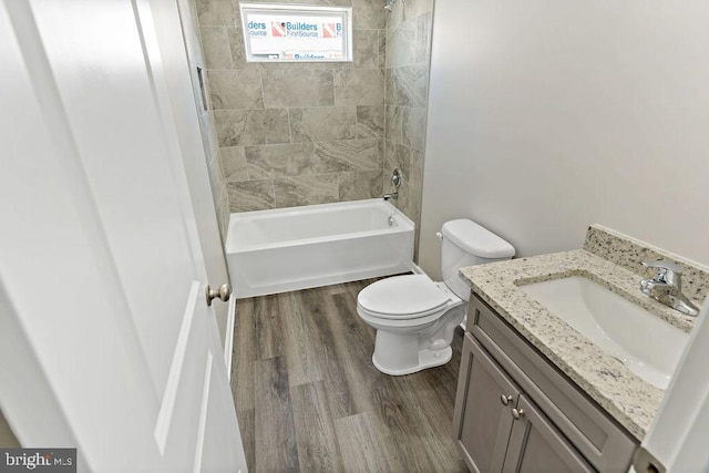 full bathroom featuring tiled shower / bath, vanity, hardwood / wood-style floors, and toilet