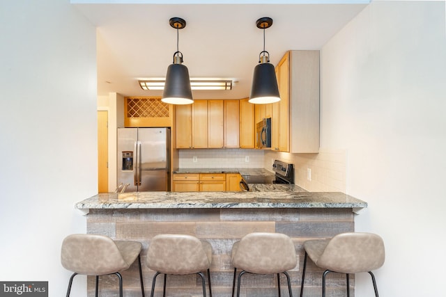 kitchen with tasteful backsplash, light brown cabinetry, a breakfast bar area, and appliances with stainless steel finishes