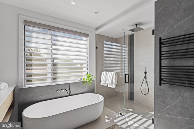 bathroom with tile walls, independent shower and bath, radiator heating unit, and tile patterned flooring