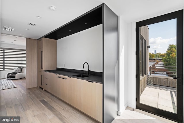 kitchen featuring light brown cabinetry, sink, and light wood-type flooring