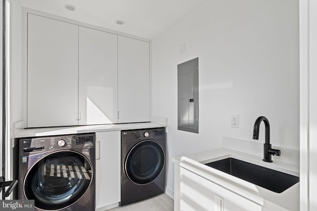 clothes washing area featuring sink, electric panel, washing machine and dryer, and cabinets