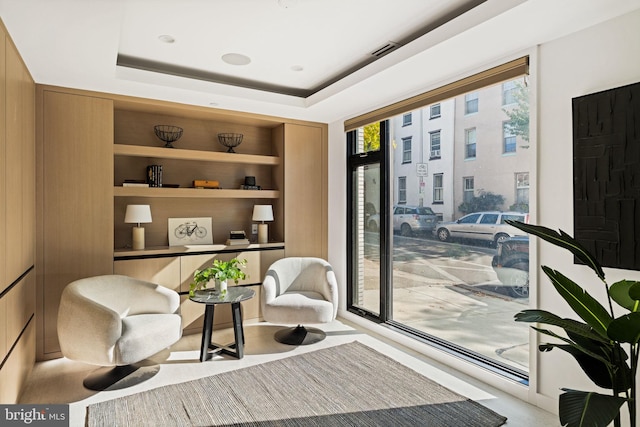 living area with a tray ceiling and wooden walls