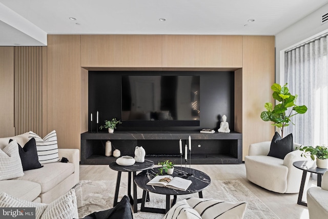 living room featuring light wood-type flooring and wood walls