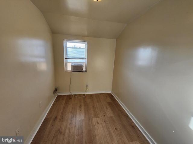 unfurnished room featuring lofted ceiling, cooling unit, and light hardwood / wood-style floors