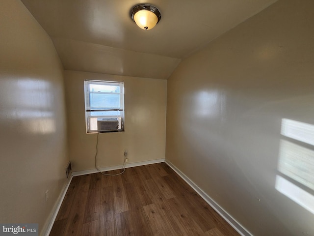 empty room with cooling unit, dark wood-type flooring, and vaulted ceiling