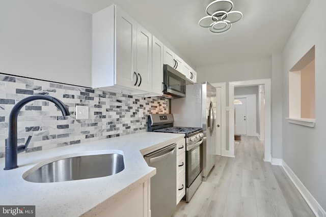 kitchen with white cabinetry, appliances with stainless steel finishes, sink, and light wood-type flooring