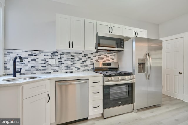 kitchen featuring white cabinets, stainless steel appliances, sink, and light wood-type flooring