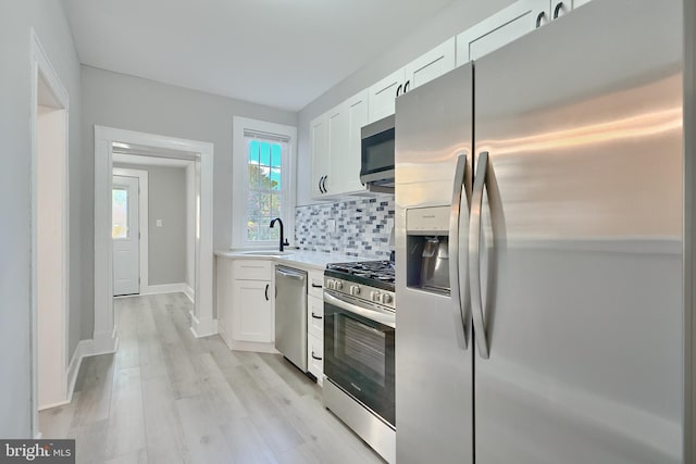 kitchen featuring white cabinetry, stainless steel appliances, tasteful backsplash, and sink