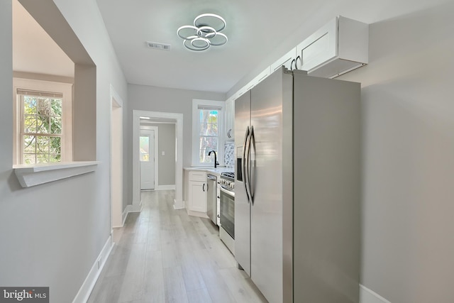 kitchen featuring appliances with stainless steel finishes, plenty of natural light, and white cabinets