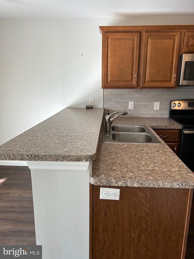 kitchen featuring kitchen peninsula, tasteful backsplash, dark hardwood / wood-style flooring, sink, and electric range oven