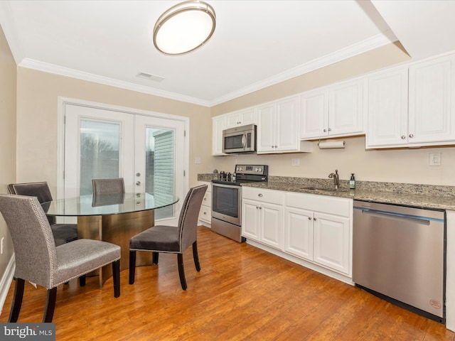 kitchen featuring appliances with stainless steel finishes, french doors, sink, light hardwood / wood-style floors, and white cabinetry