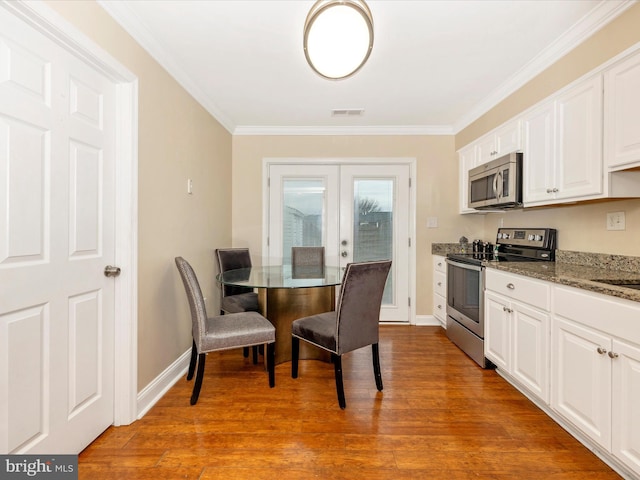 kitchen featuring white cabinets, light hardwood / wood-style floors, appliances with stainless steel finishes, and dark stone counters