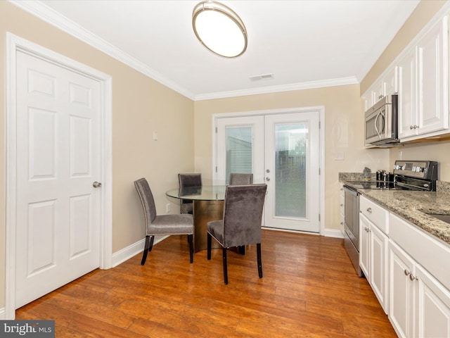 dining room with french doors, crown molding, and light hardwood / wood-style flooring