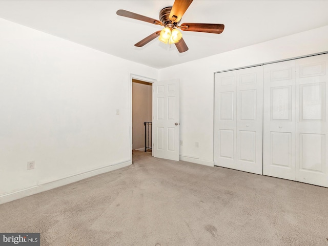 unfurnished bedroom featuring ceiling fan, light colored carpet, and a closet