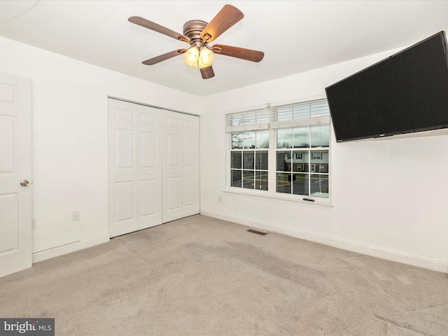 unfurnished bedroom featuring ceiling fan, light colored carpet, and a closet