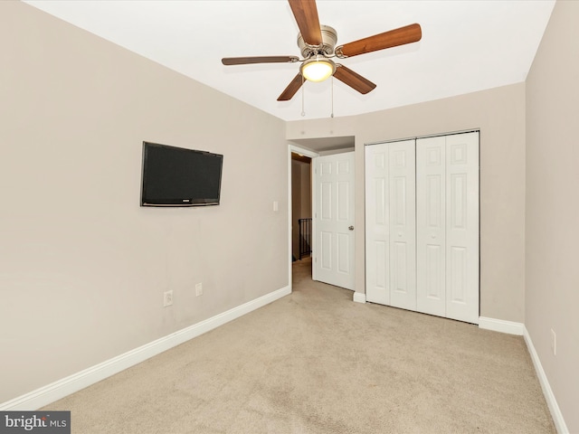 unfurnished bedroom featuring light carpet, a closet, and ceiling fan