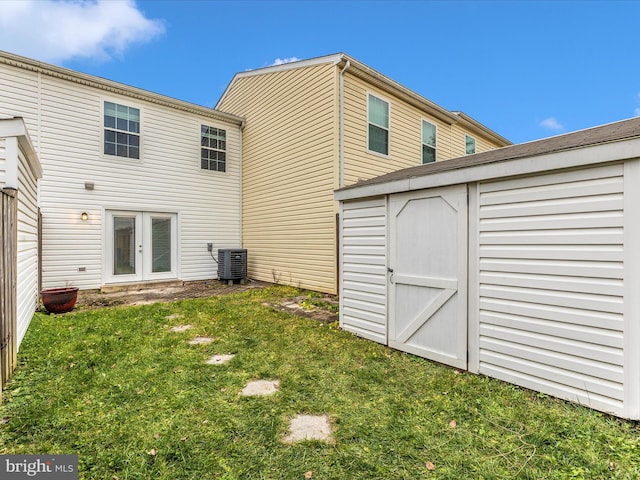 rear view of property with french doors, a lawn, a storage shed, and central air condition unit