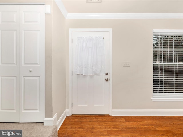 foyer entrance with wood-type flooring and crown molding