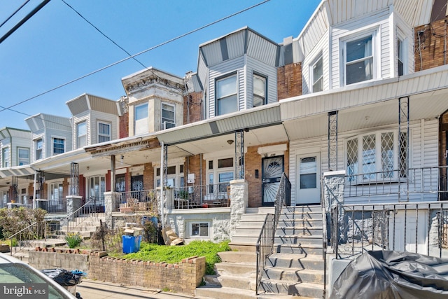 townhome / multi-family property featuring stairway, brick siding, and covered porch