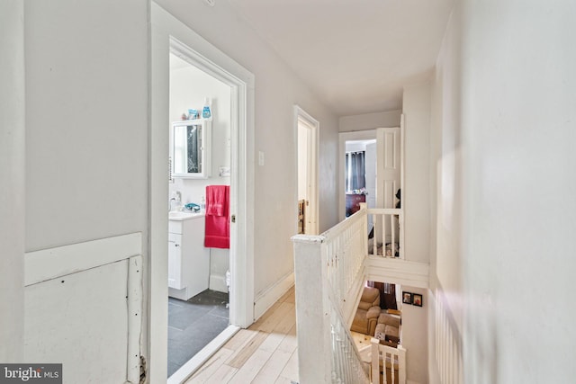 hallway with an upstairs landing and light wood-type flooring