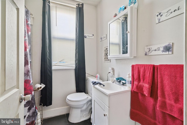 bathroom with toilet, vanity, baseboards, and tile patterned flooring