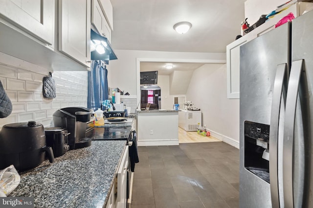 kitchen with stainless steel fridge, tasteful backsplash, dark stone counters, dark hardwood / wood-style floors, and white cabinetry