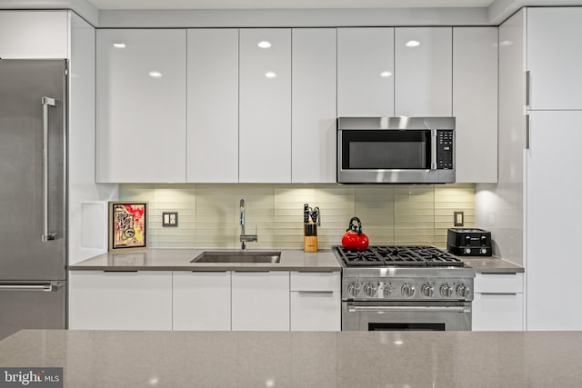 kitchen featuring a sink, white cabinetry, decorative backsplash, modern cabinets, and high quality appliances