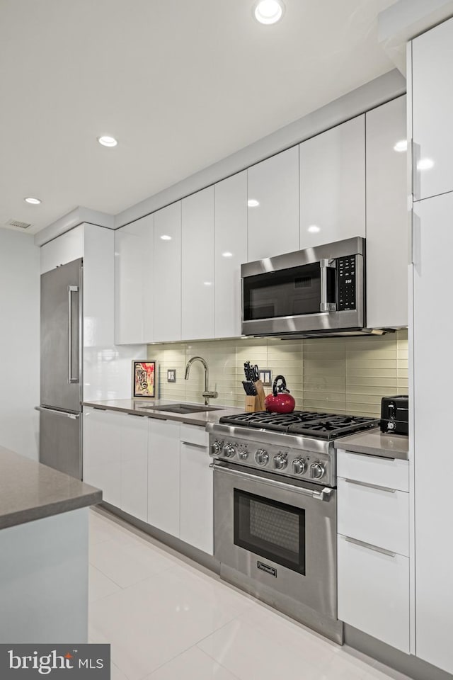 kitchen featuring high quality appliances, a sink, modern cabinets, white cabinets, and visible vents