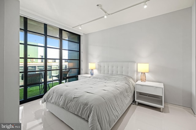 bedroom with rail lighting, light tile patterned flooring, and multiple windows