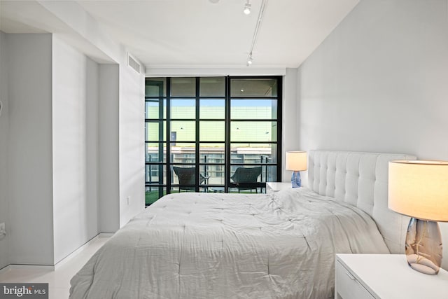 bedroom with floor to ceiling windows, rail lighting, and access to outside