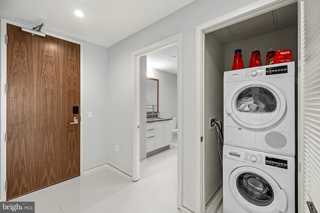 laundry room featuring recessed lighting, baseboards, stacked washing maching and dryer, and a sink