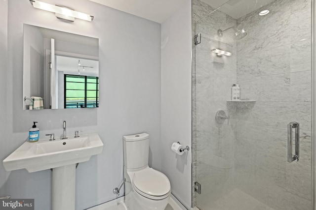 bathroom featuring baseboards, toilet, and a stall shower
